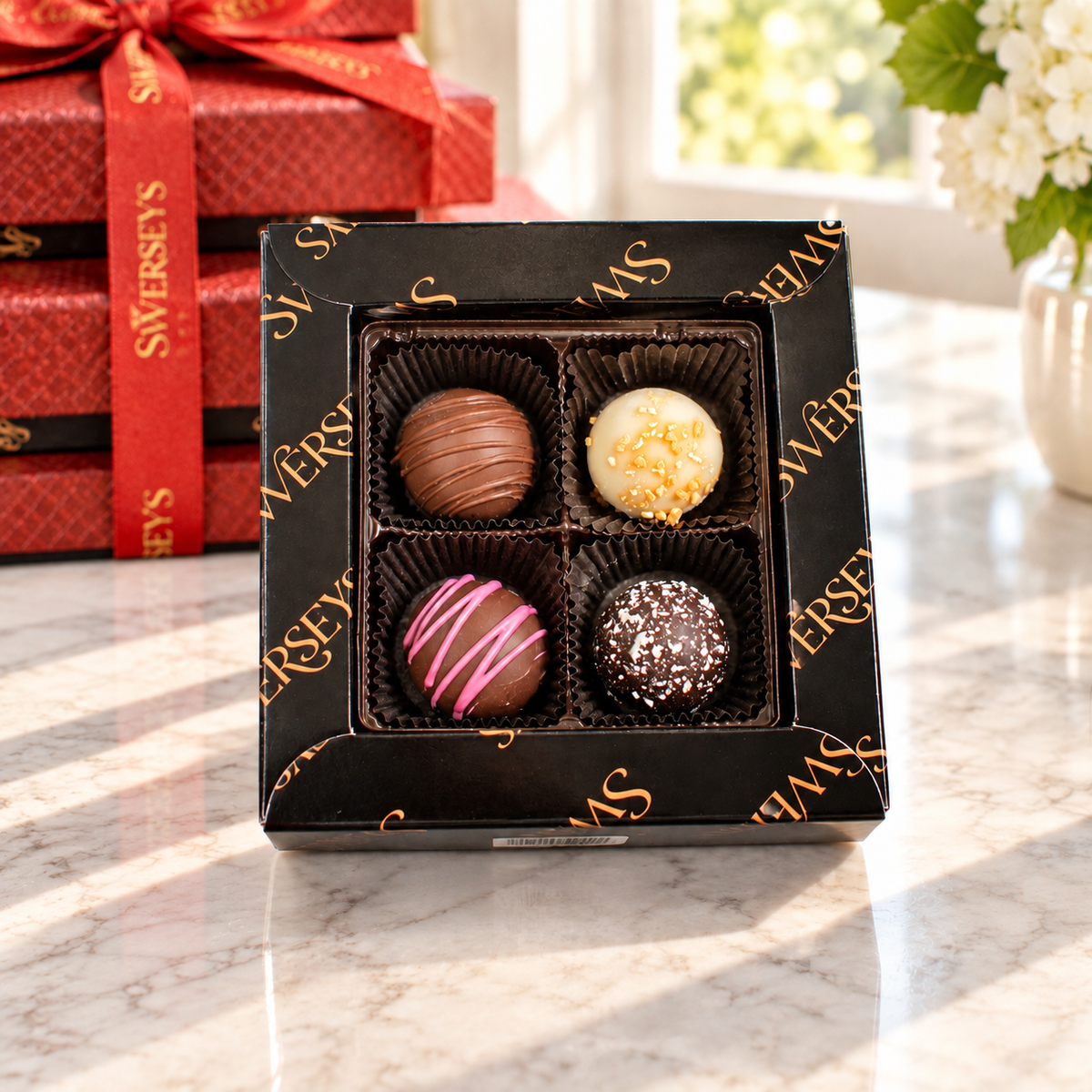 Kosherline 3 tier chocolate gift tower featuring a box of assorted gourmet truffles with pink drizzle and nut topping.