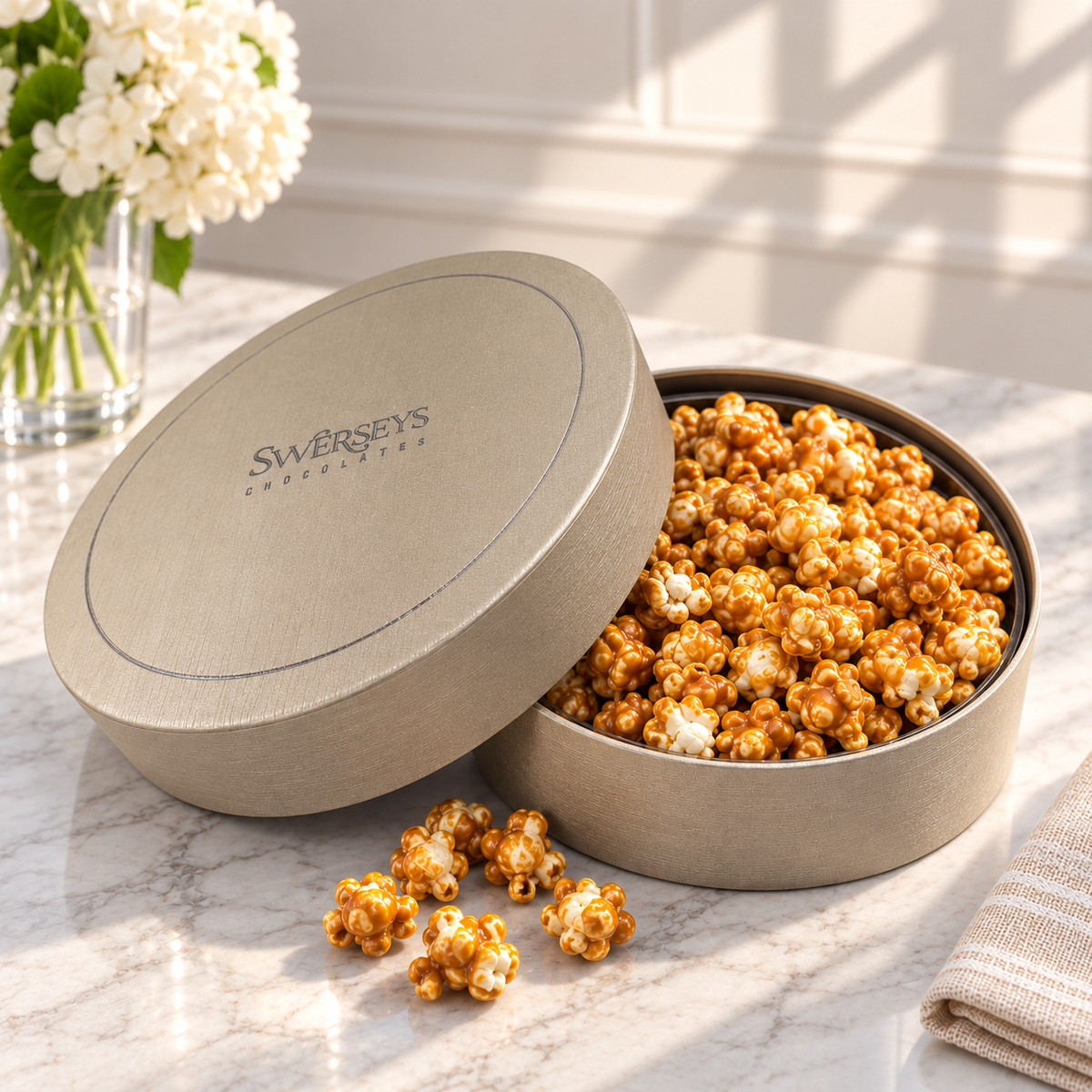 Kosherline 3 tier gift set featuring a round gold tin filled with caramel popcorn on a marble table