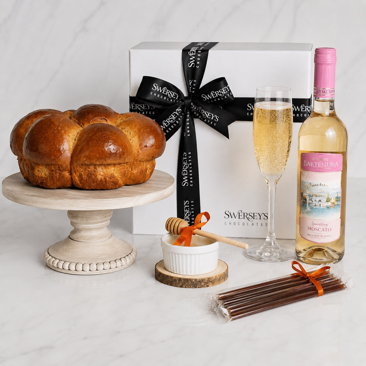 Kosherline Shabbat and Yom Tov gift box featuring a fresh challah, Bartenura Moscato, honey sticks, and a dipper.