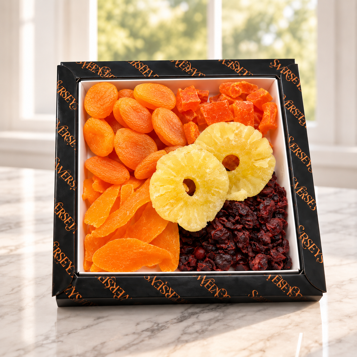 Kosherline 3 tier gourmet dried fruit gift box featuring apricots, pineapple, papaya, and raisins on marble surface
