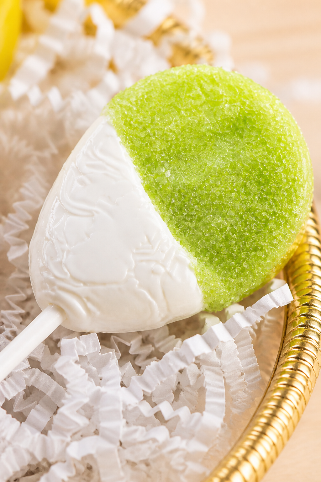 Kosherline gourmet lollipop with green sugar-coated and white chocolate dipped halves in a golden basket