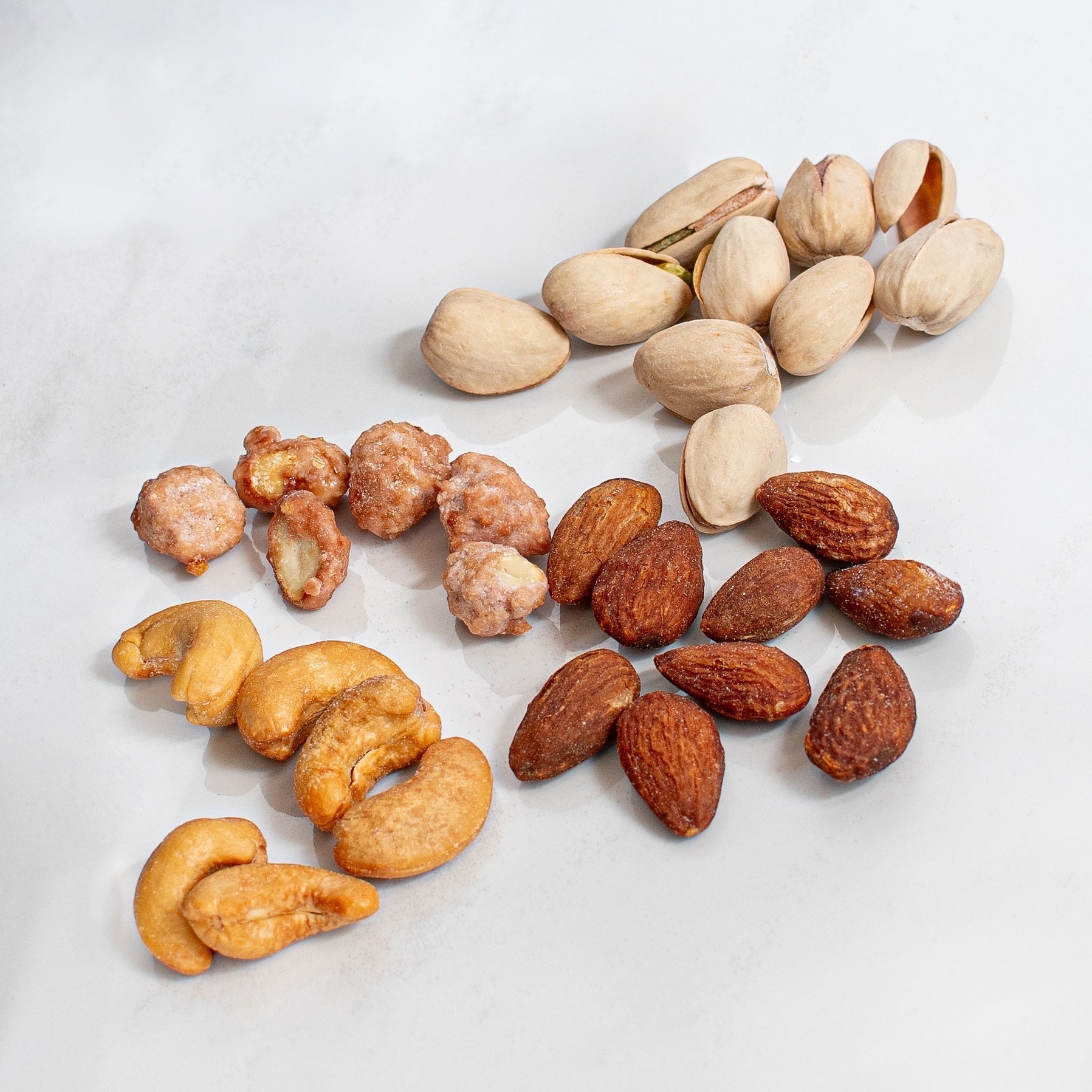 Kosherline gourmet nut assortment including roasted almonds, salted cashews, pistachios, and sugar-coated nuts.