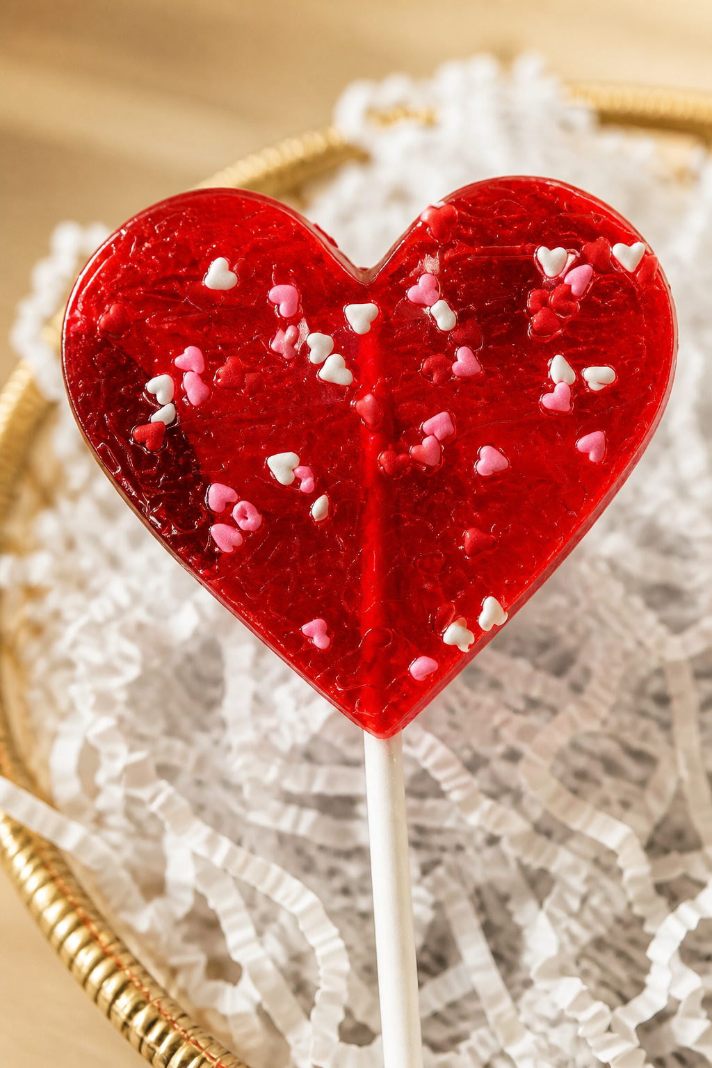 Kosherline heart-shaped red lollipop with tiny heart sprinkles in a golden basket with white filler
