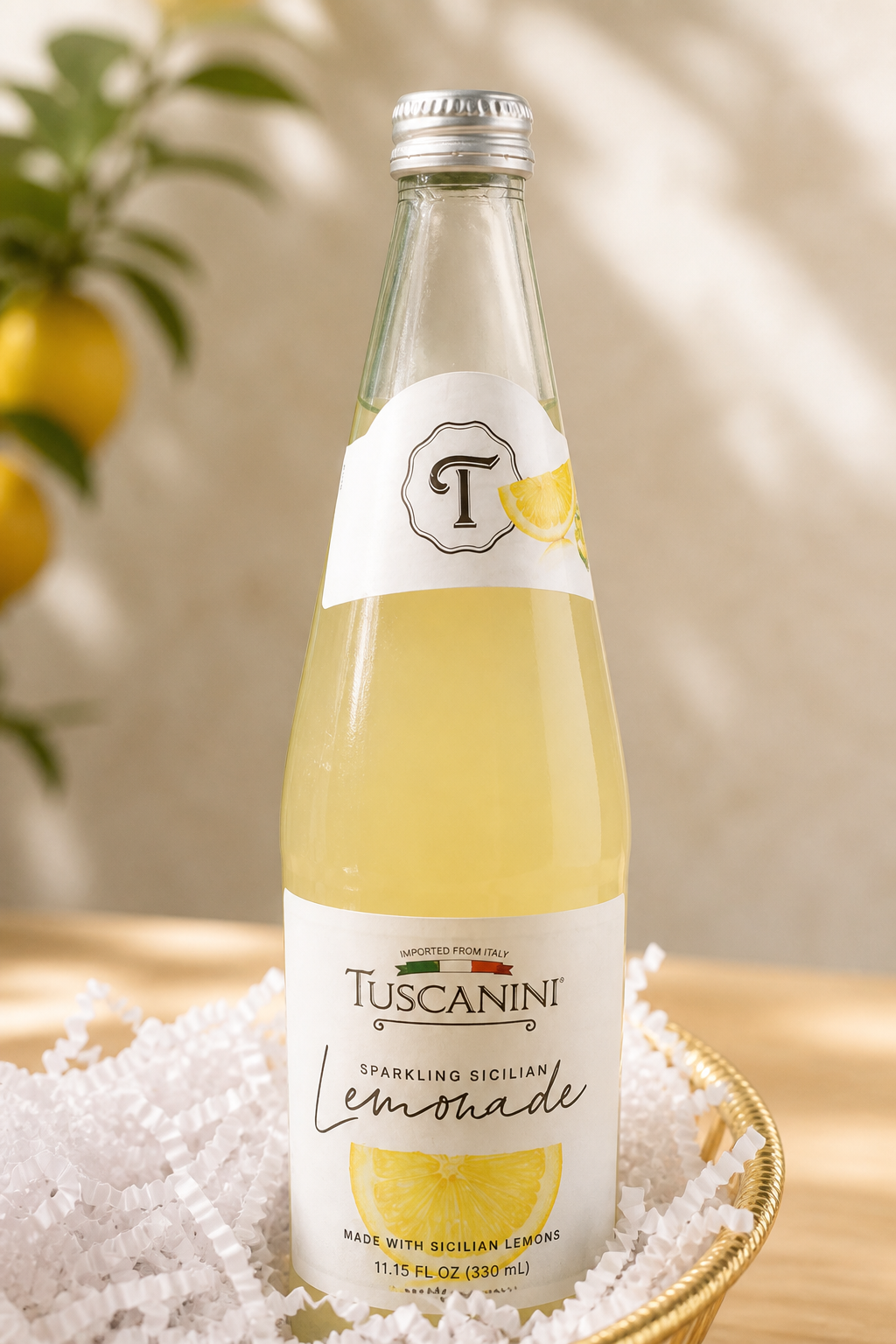 Kosherline sparkling Sicilian lemonade in a glass bottle nestled in a golden basket with white filler