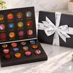 Kosherline Swerseys artistic truffles in a black gift box with a white branded ribbon on a marble countertop