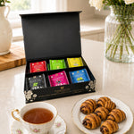 Kosherline gift box with six assorted Wissotzky teas and a plate of cinnamon twist pastries next to a teacup.