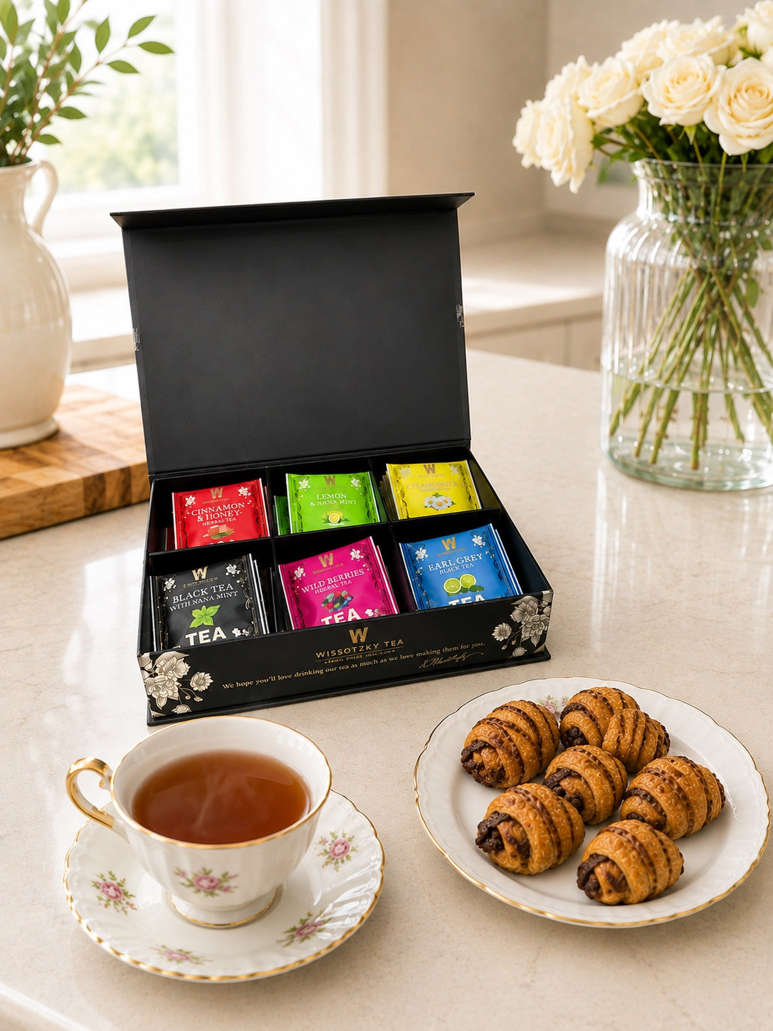 Kosherline gift box with six assorted Wissotzky teas and a plate of cinnamon twist pastries next to a teacup.