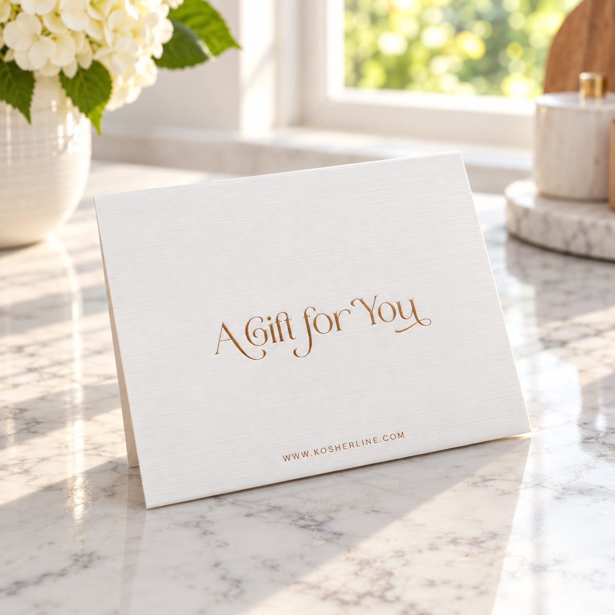 Kosherline white textured gift card with elegant gold foil lettering reading A Gift for You on a marble surface