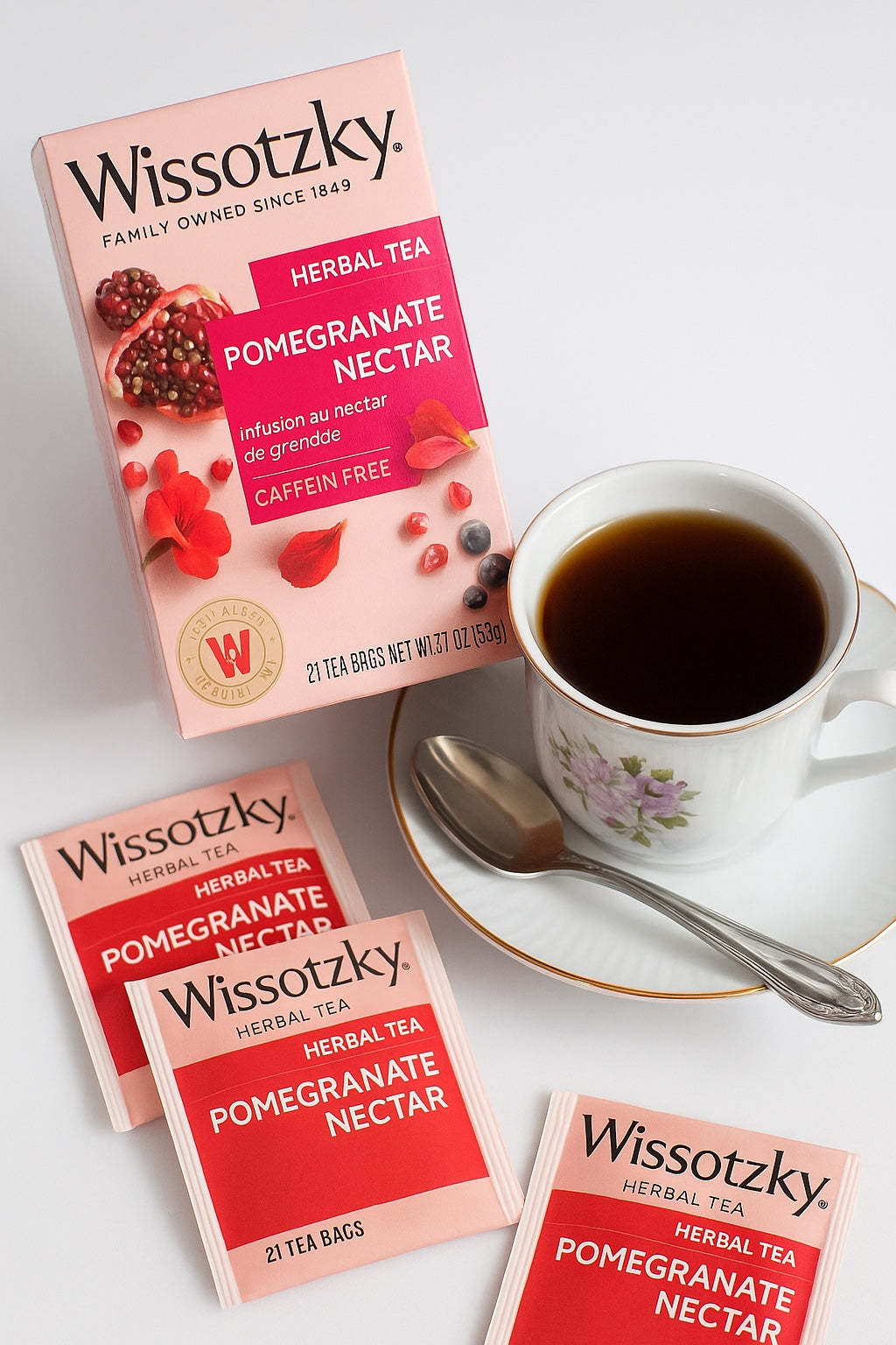 Kosherline Wissotzky pomegranate nectar herbal tea box and tea bags with a cup of tea and a silver spoon